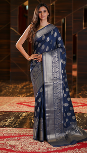 The Handlooms navy blue pure linen Banarasi saree with silver zari border and paisley motifs. Handwoven elegance.